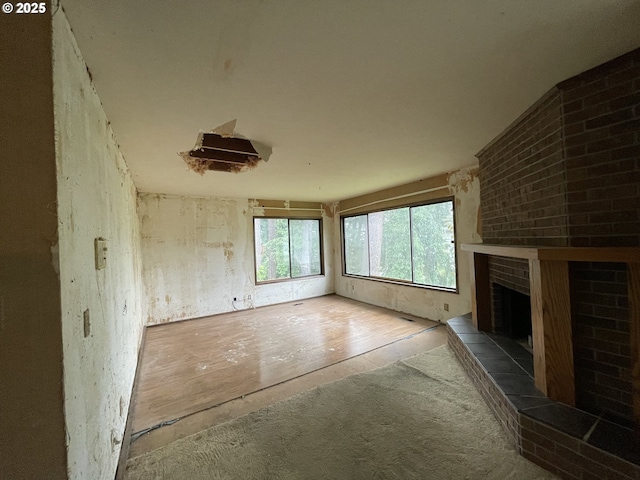 unfurnished living room featuring a brick fireplace and carpet floors