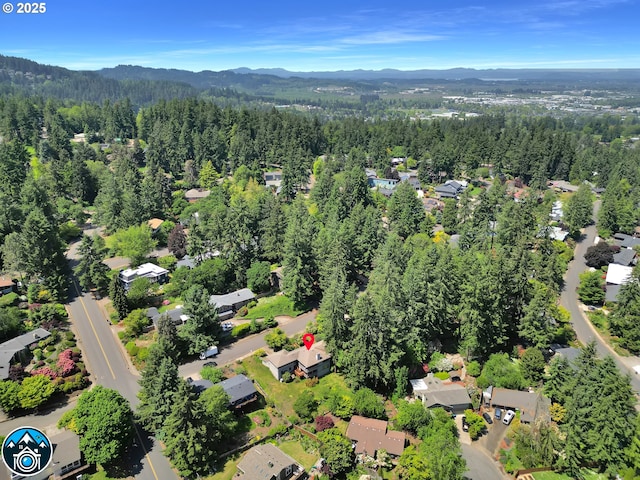 aerial overview of property's location with a mountainous background, a forest, and nearby suburban area