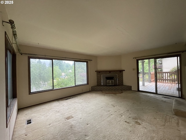 unfurnished living room featuring healthy amount of natural light, carpet flooring, and a brick fireplace