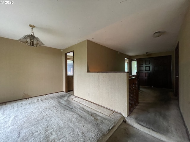 empty room featuring a chandelier and concrete flooring