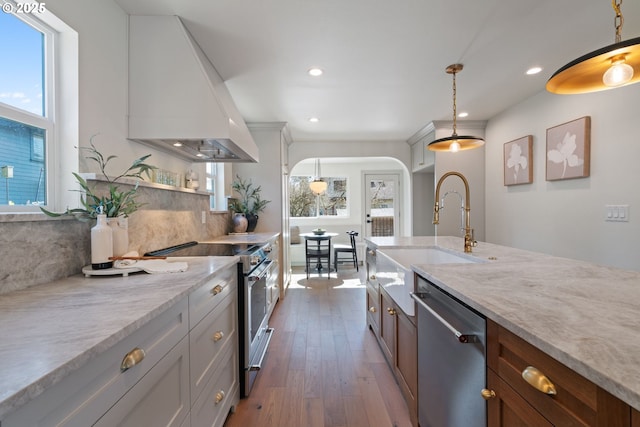 kitchen featuring stainless steel appliances, premium range hood, a sink, dark wood-style floors, and tasteful backsplash