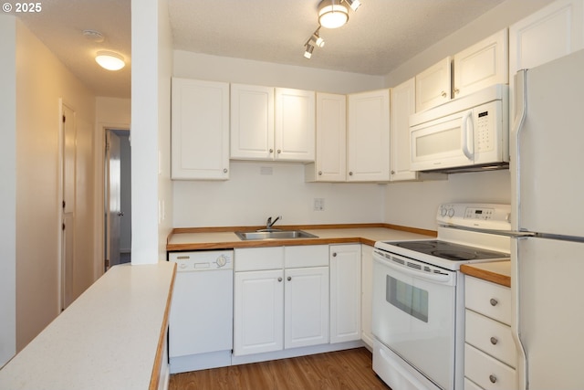 kitchen with sink, white cabinets, white appliances, and hardwood / wood-style flooring