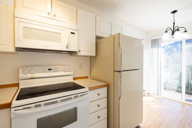 kitchen featuring white appliances, hanging light fixtures, light wood-type flooring, a notable chandelier, and white cabinetry