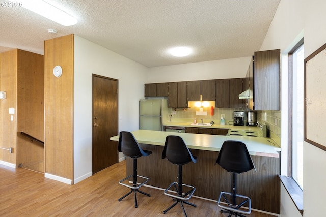 kitchen with kitchen peninsula, stainless steel fridge, and a textured ceiling