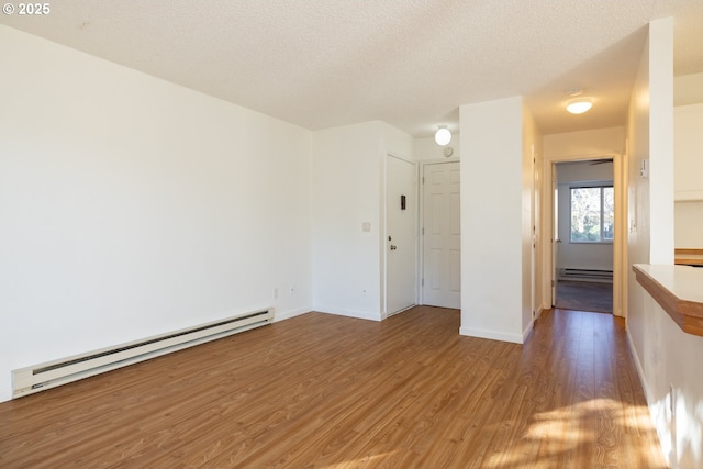 unfurnished room with wood-type flooring, a textured ceiling, and a baseboard heating unit