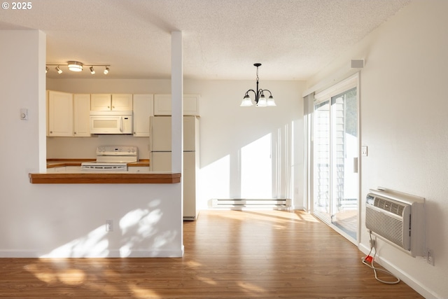 kitchen featuring kitchen peninsula, white appliances, a notable chandelier, hardwood / wood-style floors, and hanging light fixtures