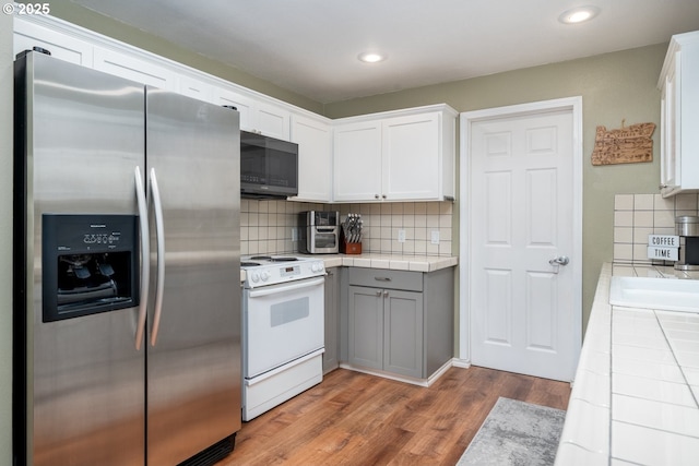 33218 SW Day St, Scappoose, OR 97056 - kitchen with stainless steel fridge, white electric range oven, tile countertops, wood finished floors, and decorative backsplash