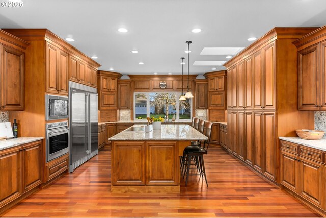 kitchen with decorative light fixtures, sink, wood-type flooring, and a healthy amount of sunlight