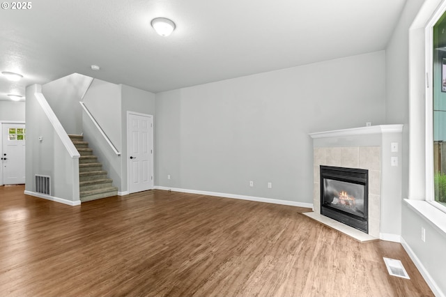 21125 SW Ladyfern Dr, Sherwood, OR 97140 - unfurnished living room with wood finished floors, stairway, a tiled fireplace, and baseboards