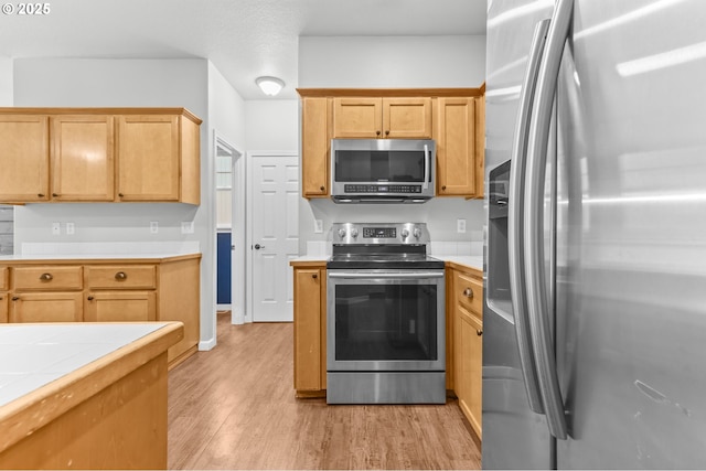 21125 SW Ladyfern Dr, Sherwood, OR 97140 - kitchen featuring stainless steel appliances, light wood-type flooring, and tile countertops