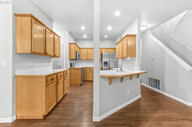 21125 SW Ladyfern Dr, Sherwood, OR 97140 - kitchen featuring stainless steel appliances, a peninsula, dark wood-style floors, a kitchen bar, and a sink