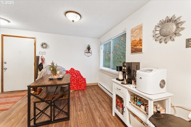 interior space with wood-type flooring, a textured ceiling, and baseboard heating