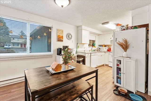 dining area featuring a baseboard radiator, a textured ceiling, and light wood-type flooring