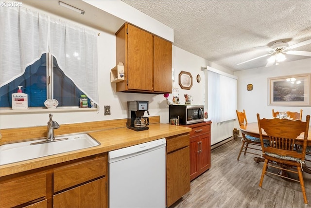 kitchen featuring ceiling fan, sink, white dishwasher, a textured ceiling, and light wood-type flooring