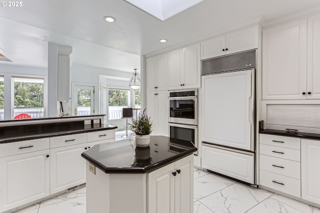 kitchen featuring paneled fridge, double oven, light marble finish flooring, dark countertops, and recessed lighting