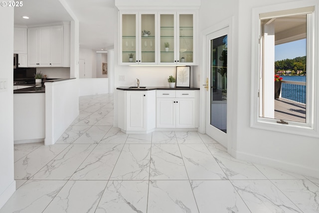 1308 Northshore Rd, Lake Oswego, OR 97034 - kitchen with light marble finish flooring, dark countertops, white cabinets, glass insert cabinets, and recessed lighting