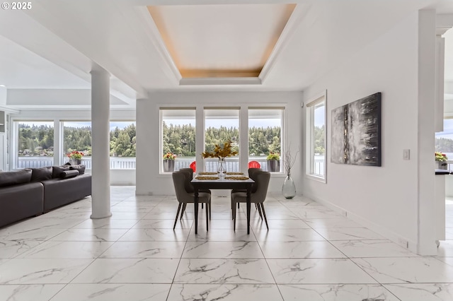 dining room featuring light marble finish flooring, baseboards, a tray ceiling, and ornate columns
