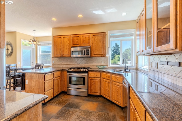 308 SW 38th Loop, Gresham, OR 97080 - kitchen featuring stainless steel appliances, brown cabinets, a peninsula, decorative backsplash, and dark stone counters
