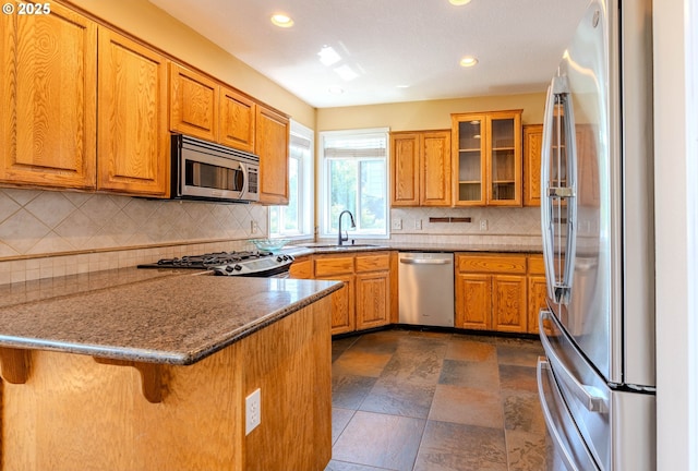 308 SW 38th Loop, Gresham, OR 97080 - kitchen with appliances with stainless steel finishes, a peninsula, brown cabinetry, recessed lighting, and glass insert cabinets