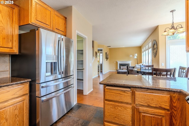 308 SW 38th Loop, Gresham, OR 97080 - kitchen featuring stainless steel refrigerator with ice dispenser, a fireplace, brown cabinets, and decorative backsplash