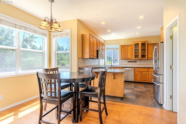 308 SW 38th Loop, Gresham, OR 97080 - kitchen with appliances with stainless steel finishes, a chandelier, brown cabinets, decorative backsplash, and glass insert cabinets