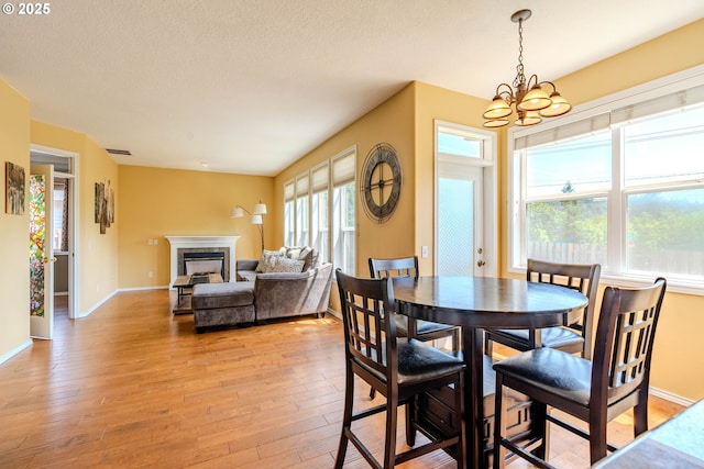 308 SW 38th Loop, Gresham, OR 97080 - dining room featuring a chandelier, a fireplace, light wood finished floors, and a textured ceiling
