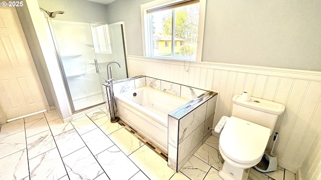 full bathroom featuring a shower stall, marble finish floor, toilet, wainscoting, and a garden tub