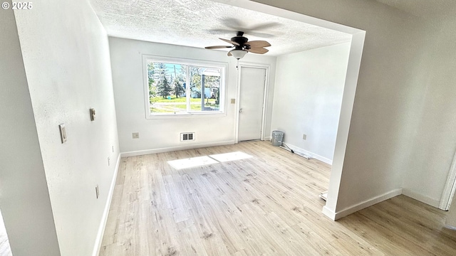unfurnished room with wood finished floors, a textured ceiling, baseboards, and visible vents