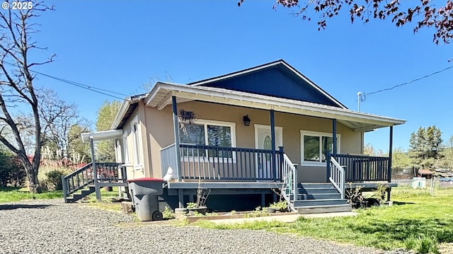 view of front of home with stucco siding, stairs, and covered porch