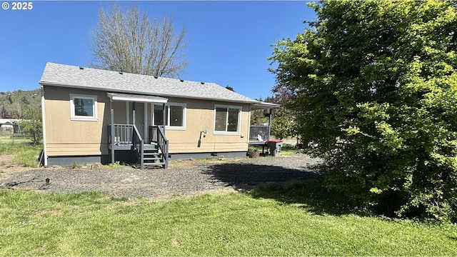 back of property with a lawn and a shingled roof