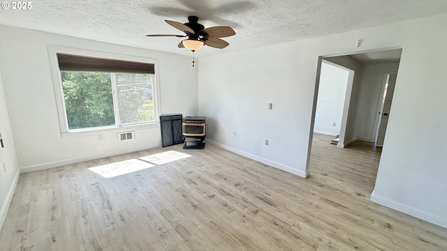 spare room with a wood stove, wood finished floors, visible vents, and baseboards