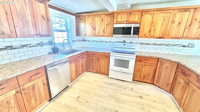 kitchen with light wood-type flooring, decorative backsplash, a sink, and appliances with stainless steel finishes