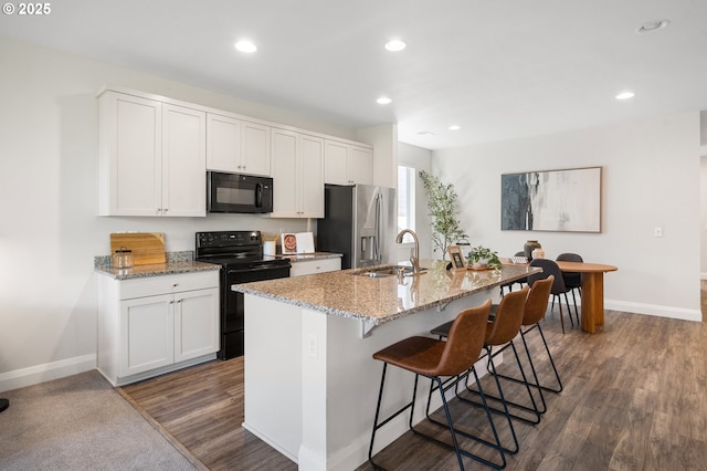 2310 S Heather St, Cornelius, OR 97113 - kitchen featuring black appliances, dark wood-style floors, a kitchen island with sink, a kitchen bar, and white cabinetry