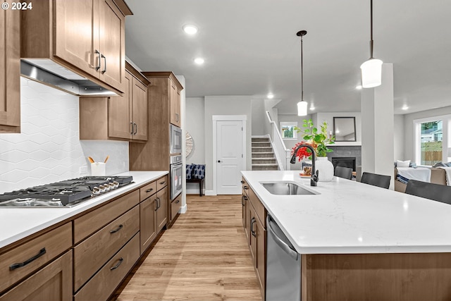 kitchen featuring stainless steel appliances, a kitchen island with sink, sink, and pendant lighting