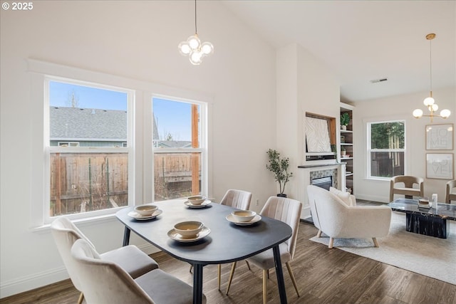 dining room with a wealth of natural light, a chandelier, wood finished floors, and a tile fireplace