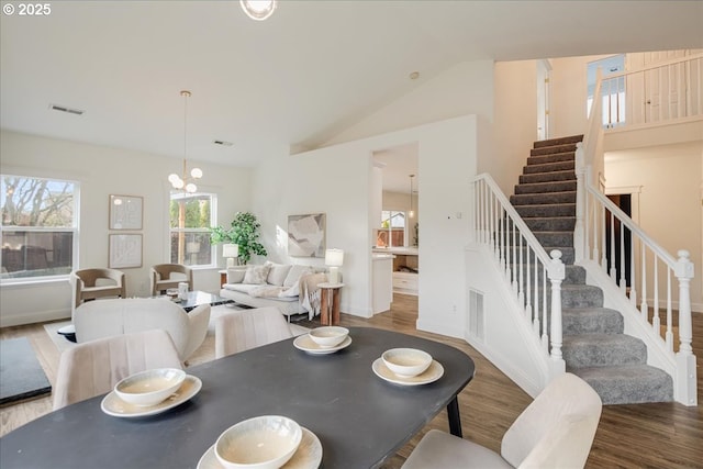dining room with stairs, wood finished floors, visible vents, and lofted ceiling