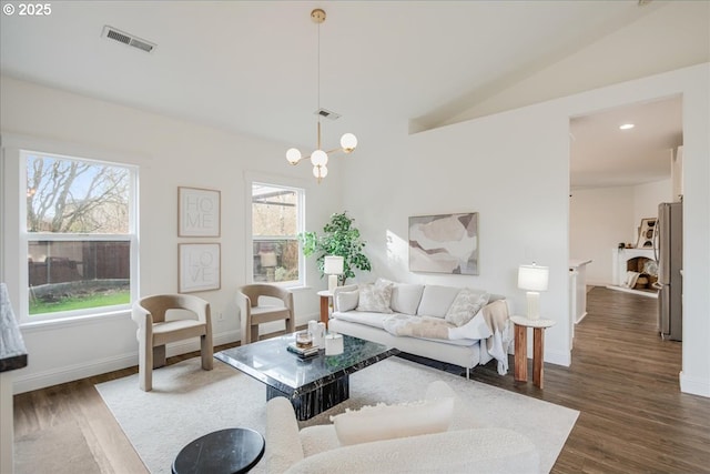 living room with vaulted ceiling, dark wood finished floors, visible vents, and an inviting chandelier