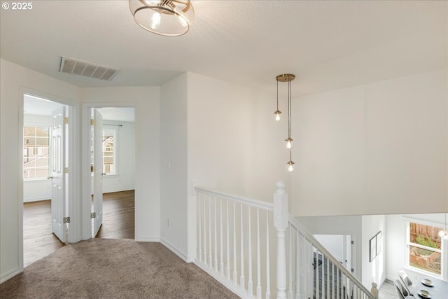 hallway featuring carpet, an upstairs landing, visible vents, and baseboards