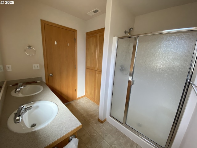 bathroom featuring double vanity, a stall shower, a sink, and visible vents