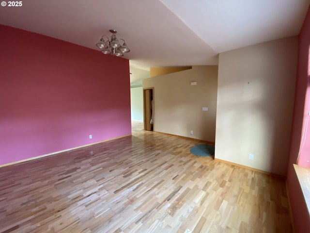 empty room with baseboards, wood finished floors, and an inviting chandelier