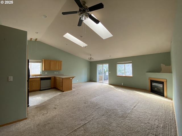 unfurnished living room featuring lofted ceiling with skylight, a wealth of natural light, a glass covered fireplace, and light carpet