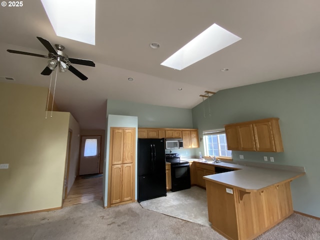 kitchen featuring a peninsula, black appliances, light carpet, and lofted ceiling with skylight