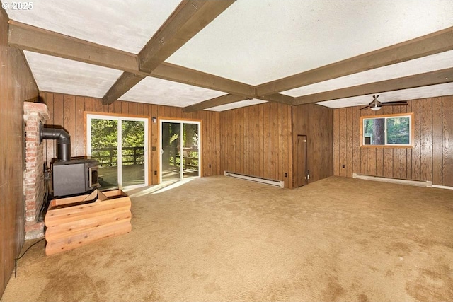 48395 High Leah Dr, Oakridge, OR 97463 - unfurnished living room with a baseboard radiator, a wood stove, beam ceiling, carpet flooring, and wooden walls