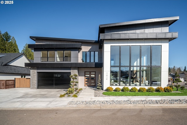 contemporary home featuring a garage, driveway, and fence