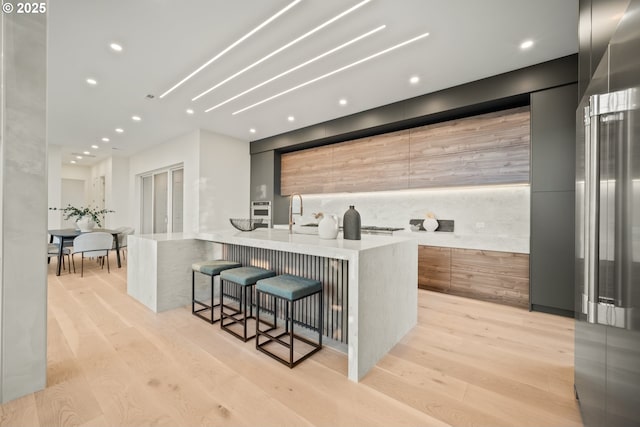 kitchen featuring light wood-style flooring, modern cabinets, a kitchen breakfast bar, and a large island