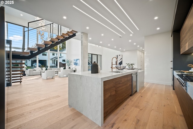 kitchen featuring open floor plan, a sink, light wood-style flooring, and modern cabinets