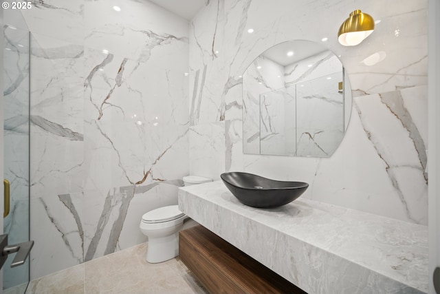 bathroom featuring stone wall, vanity, and toilet