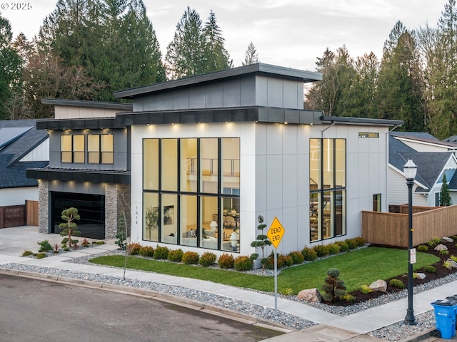 view of front of house featuring driveway, stone siding, an attached garage, and board and batten siding