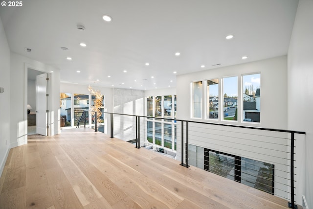 hallway featuring light wood-style floors, recessed lighting, baseboards, and an upstairs landing