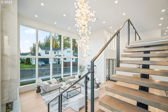 stairs with a chandelier, recessed lighting, and wood finished floors